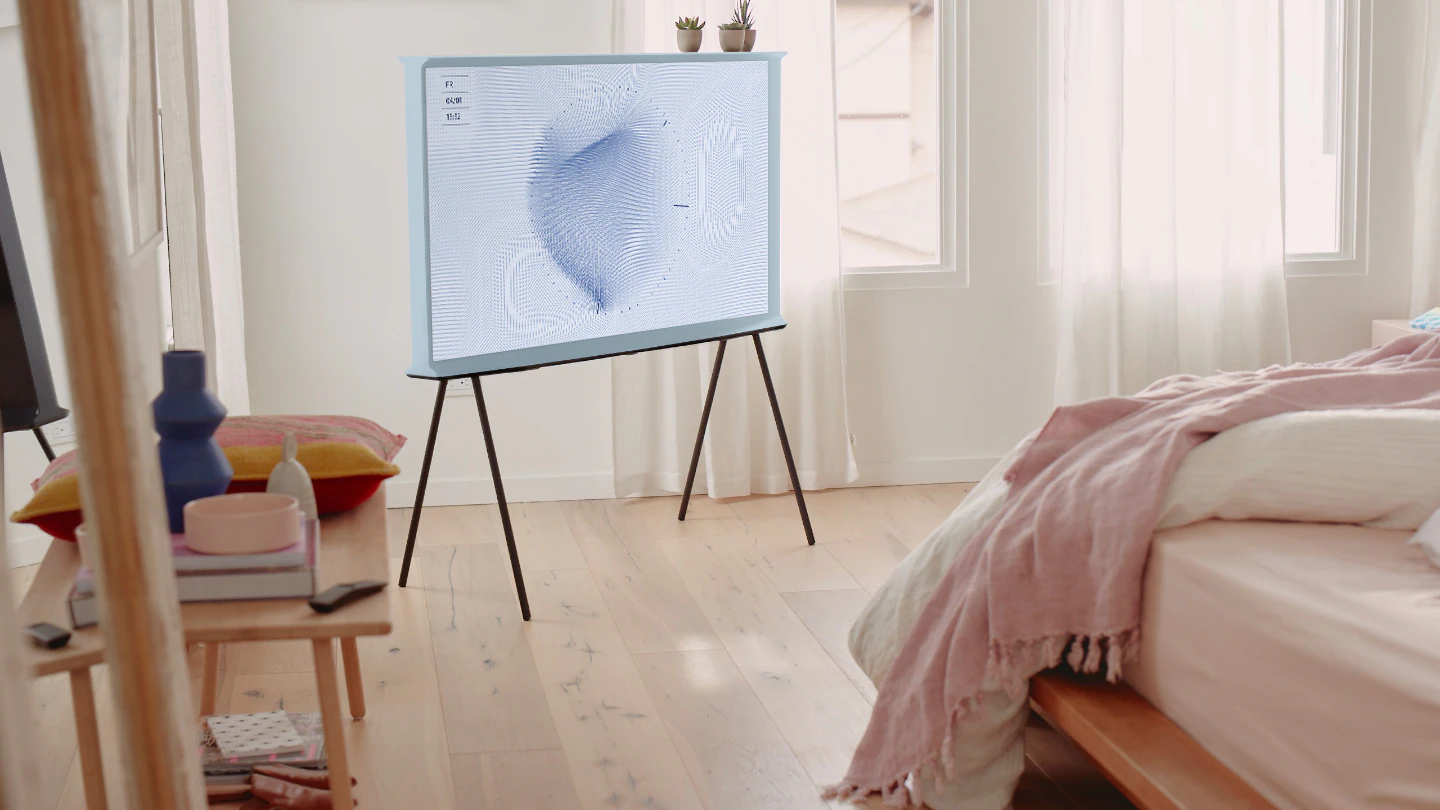 Un TV The Serif bleu gris sur ses pieds au milieu d'une chambre lumineuse.