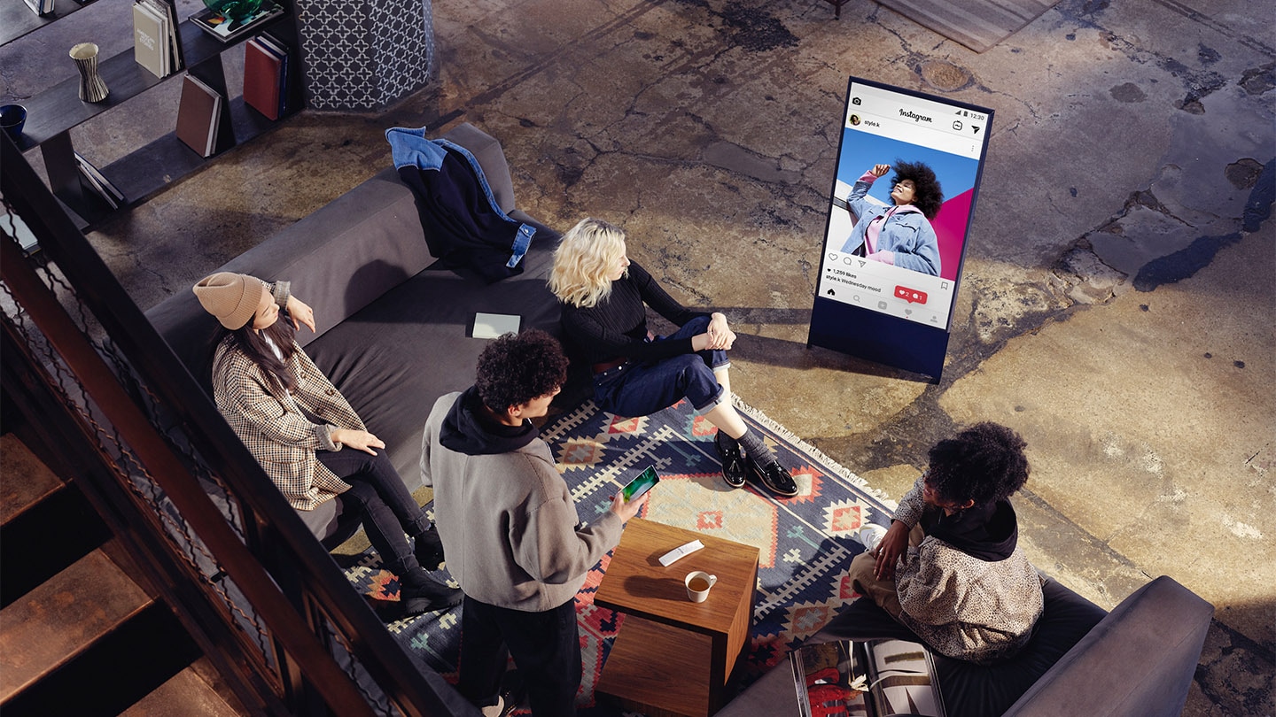 Neljä henkilöä istuu suuressa tyylikkäässä olohuoneessa ja The Sero on pystyasennossa ja näyttää heidän Instagram-kuviaan.